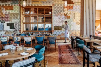 Stylish dining room with hardwood floors, area rugs, and multicolored mosaic tiles on the wall