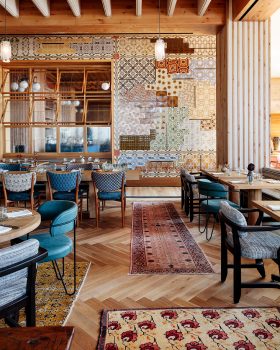 Stylish dining room with hardwood floors, area rugs, and multicolored mosaic tiles on the wall