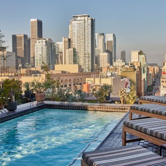 Rooftop Pool Deck with lounge chairs and view of downtown los angeles city skyline