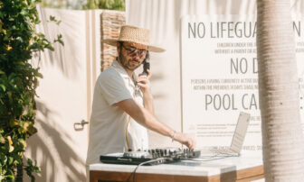 A DJ adjusts the sound system on the table while conversing on the phone.