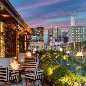 charmaines outdoor rooftop at night with firepits and view of the city skyline