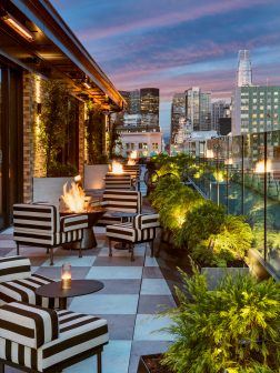 charmaines outdoor rooftop at night with firepits and view of the city skyline