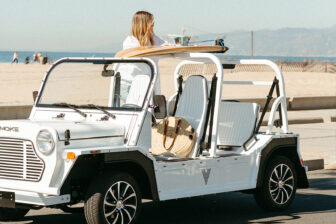 girl in moke car with surfboard